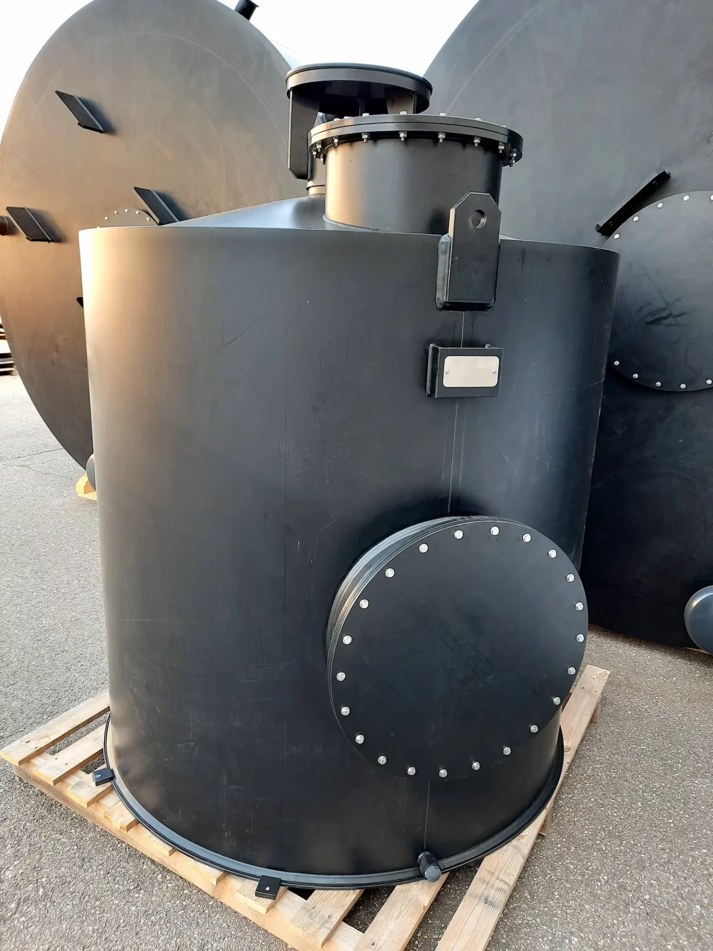 Filtre industriel à charbon actif noir, équipé d’une trappe de visite circulaire.